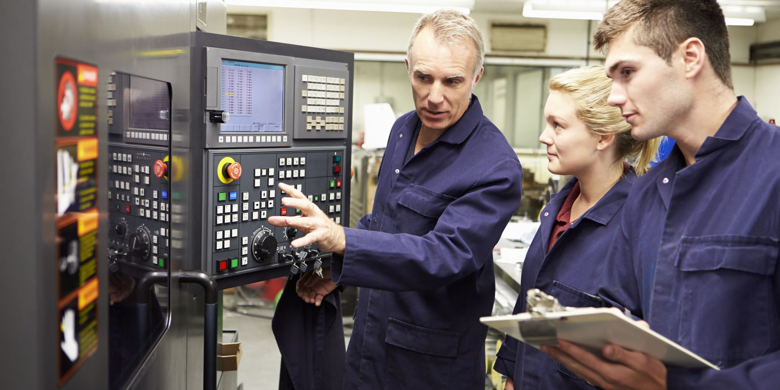 Engineer Teaching Apprentices To Use Computerized Lathe
