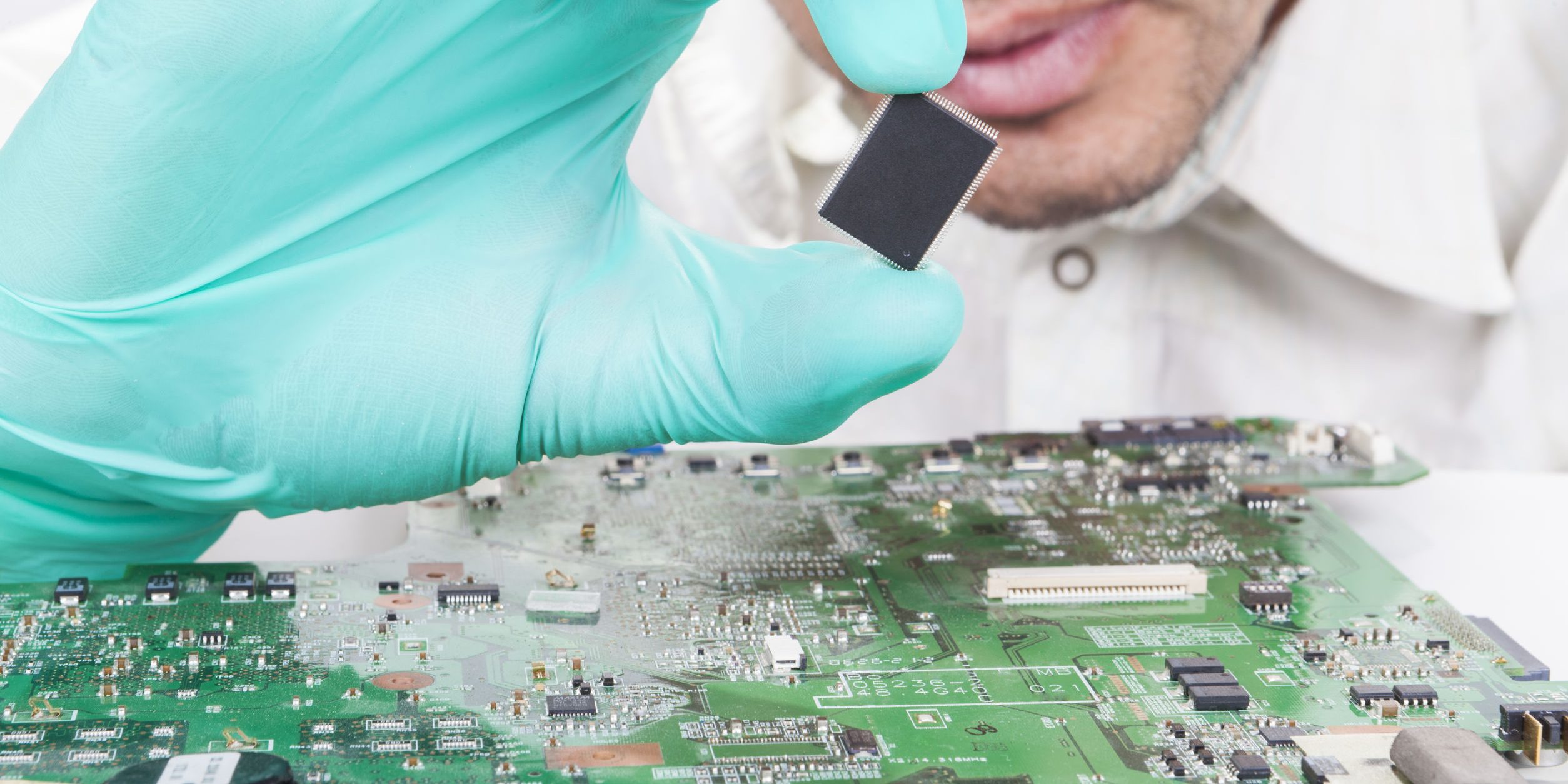Holding Microchip on electronic circuit board with Gloves Holding Microchip on electronic circuit board with Gloves