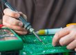 hand holding a soldering iron soldering a component to a board