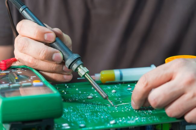soldering 101 for beginners hand holding a soldering iron soldering a component to a board